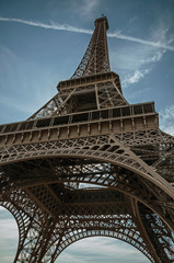 Bottom view of Eiffel Tower made in iron and Art Nouveau style, with sunny blue sky in Paris. Known...