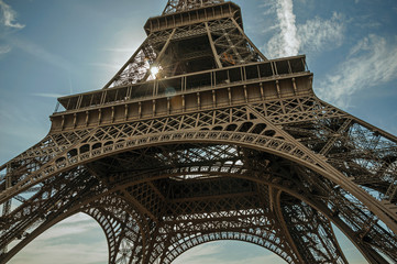 Bottom view of Eiffel Tower made in iron and Art Nouveau style, with sunny blue sky in Paris. Known...
