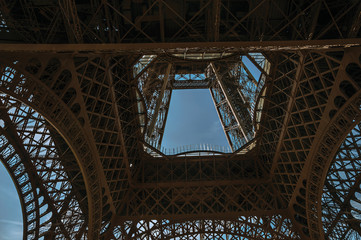 Bottom view of Eiffel Tower made in iron and Art Nouveau style, with sunny blue sky in Paris. Known as the “City of Light”, is one of the most impressive world’s cultural center. Northern France.