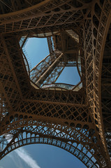 Bottom view of Eiffel Tower made in iron and Art Nouveau style, with sunny blue sky in Paris. Known...