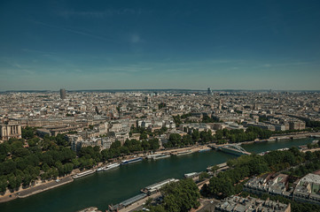 Fototapeta na wymiar Skyline, River Seine, greenery and buildings under blue sky, seen from the Eiffel Tower in Paris. Known as the “City of Light”, is one of the most impressive world’s cultural center. Northern France.