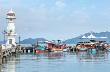 Landscape view of public white lighthouse on pier of Bang Bao fishing village with fishing boats mooring at Koh Chang Island,Trat, Thailand