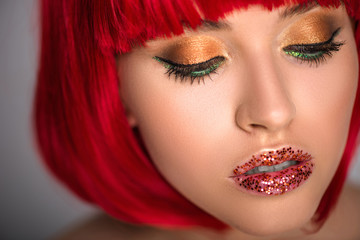attractive woman with red hair and glittering makeup looking down