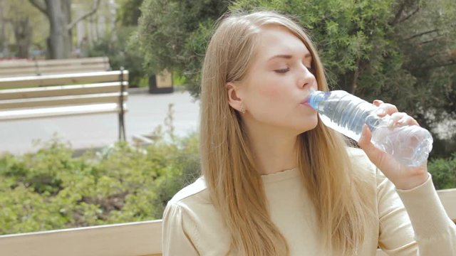 Young pretty girl drinks fresh water, outdoor  
