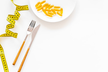 Dietary supplement for well-being. Fish oil or omega-3 capsules on plate near measuring tape on white background top view copy space