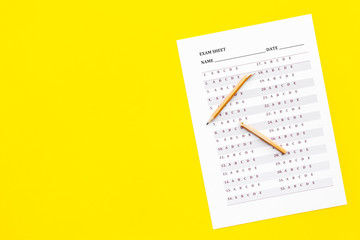Exam sheet on yellow table top view copy space. Education concept. Exam problems. Broken pencil near exam sheet