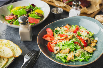 Grilled ribs with buckwheat, salad with citrus and grilled chicken liver, salad with tomato. Table with food in restaurant.