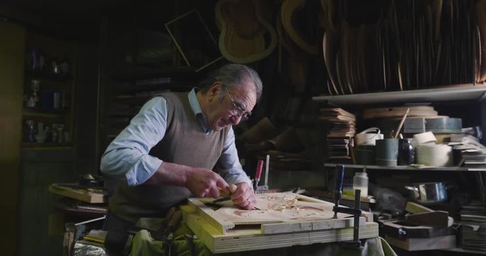 In his laboratory, a liutist builds high quality guitars for musicians, working fine wood. Concept of: music, tradition, ancient crafts.