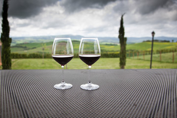 two glasses of red wine against beautiful landscape in Tuscany