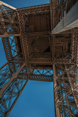 Bottom view of Eiffel Tower made in iron and Art Nouveau style, with sunny blue sky in Paris. Known as the “City of Light”, is one of the most impressive world’s cultural center. Northern France.