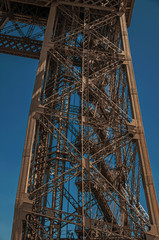 View of one leg’s iron structure of the Eiffel Tower, with sunny blue sky in Paris. Known as the “City of Light”, is one of the most impressive world’s cultural center. Northern France.
