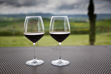 two glasses of red wine against beautiful landscape in Tuscany