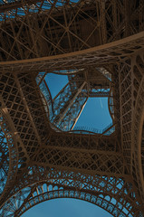 Bottom view of Eiffel Tower made in iron and Art Nouveau style, with sunny blue sky in Paris. Known...