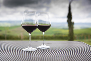 two glasses of red wine against beautiful landscape in Tuscany