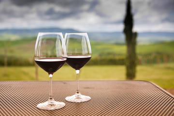 two glasses of red wine against beautiful landscape in Tuscany