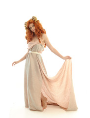 full length portrait of pretty red haired lady wearing fantasy toga gown, standing pose on white background. © faestock