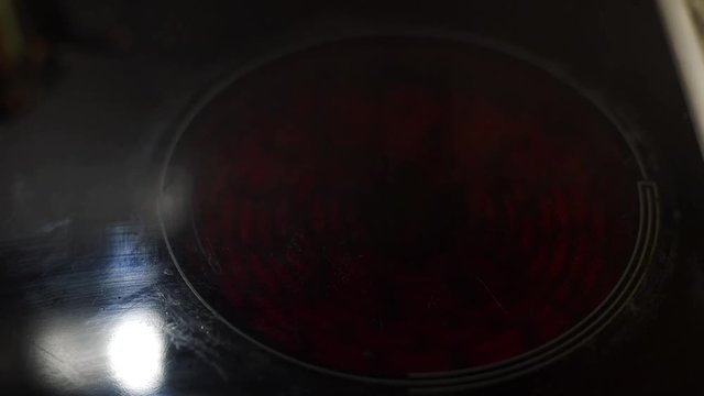 Modern electric hob being turned on and glowing bright red with heat before cooking in the kitchen.