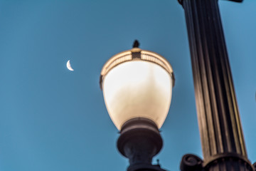 Old street lamp, symbol of the city of Sao Paulo, Brazil, with the moon at the background, at late afternoon.