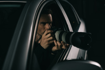 focused paparazzi doing surveillance by camera from his car