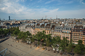 Buildings in square and Eiffel Tower on the horizon seen from the Center Georges Pompidou in Paris. Known as the “City of Light”, is one of the most impressive world’s cultural center. Northern France