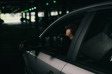 Fototapeta na wymiar male paparazzi doing surveillance by camera with object glass from his car