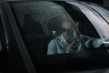 male undercover agent using talkie walkie and spying from car