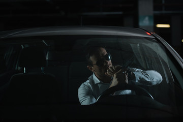 serious male undercover agent in sunglasses charging gun in car