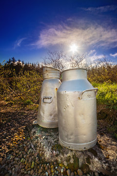 Close view of two aluminum milk cans on the roadside in a county Cork