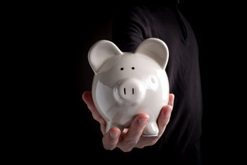 Man with a piggy bank in his hands on a black background
