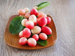 Carissa carandas or karonda are white and red with green leaves in wooden plates. On the old wood table It is a small fruit and has medicinal properties. Vitamin C is high when cooked to sour taste.