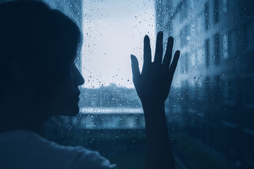 sad lonely depression mood woman silhouette touch glass windows rainy dark day outside - obrazy, fototapety, plakaty