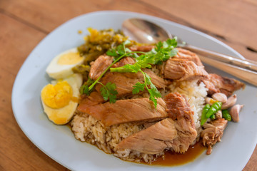 Popular Thai food of Stewed pork leg on rice on wooden table.