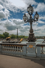Fototapeta na wymiar Golden statue and lighting post adorning the Alexandre III bridge over the Seine River and Eiffel Tower in Paris. Known as one of the most impressive world’s cultural center. Northern France.