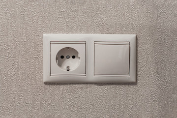 Socket and switch on beige wall close-up