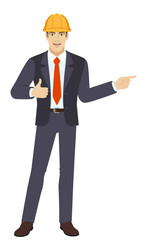 Businessman in construction helmet showing thumb up and pointing somewhere