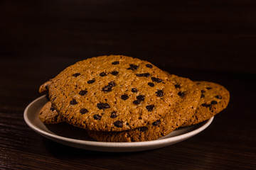 Plate with chocolate chip cookies on a dark wooden table