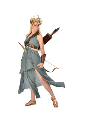 full length portrait of pretty blonde lady wearing fantasy toga gown,  and holding a bow and arrow. standing pose on white background.