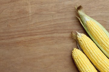 Fresh corn on cobs on wooden background