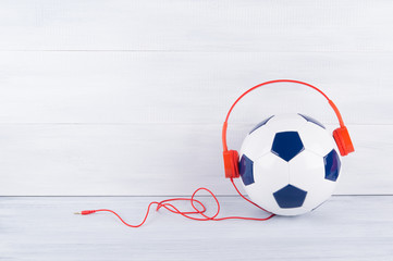 a soccer ball wearing red headphones on a gray background © kurgu128