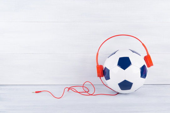 a soccer ball wearing red headphones on a gray background