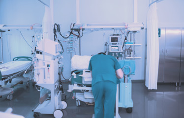 Male doctor working next to the patient bed in the critical care unit