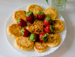 Tasty cheesecakes with fresh strawberries on a white plate