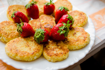 Fried cheesecakes with strawberries on a white plate