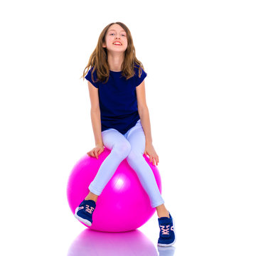 little girl doing exercises on a big ball for fitness.