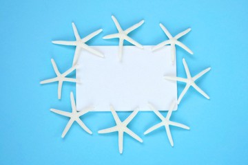 summer sea frame.white rectangular board with white dry starfish on a bright blue background.top view, copy space.Summer time.	Summer season