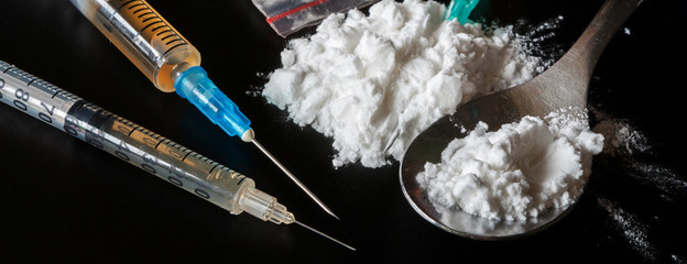 drugs heroin powder pills and syringes on a black background flat lay top view with copy space long...