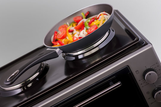 vegetables in a frying pan are cooked on modern electric stove. kitchen equipment