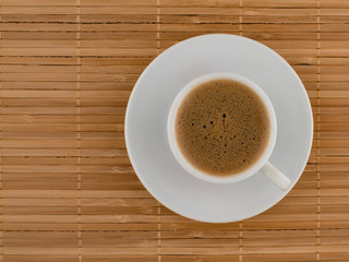 Coffee with foam in a white cup on a natural background. View from above.