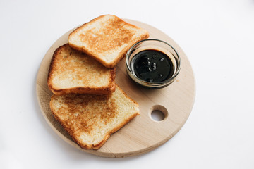 Crispy toasts and jam on wooden board