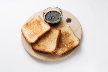 Crispy toasts and jam on wooden board